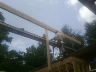 Carpenter setting a ridge beam over a new addition frame — Ice Dam Removal by Roofing Brothers in Flanagan