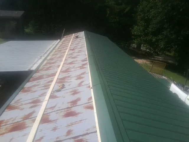 Old rusted panels beside newly installed green metal roofing — Wind Damage Roof Repair by Roofing Brothers in Flanagan