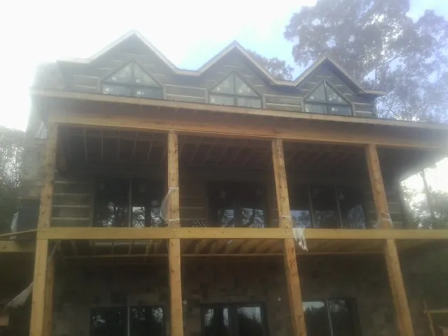 Dormers and porch framing on a large log home under construction — Roof Coating work by our crew in Flanagan