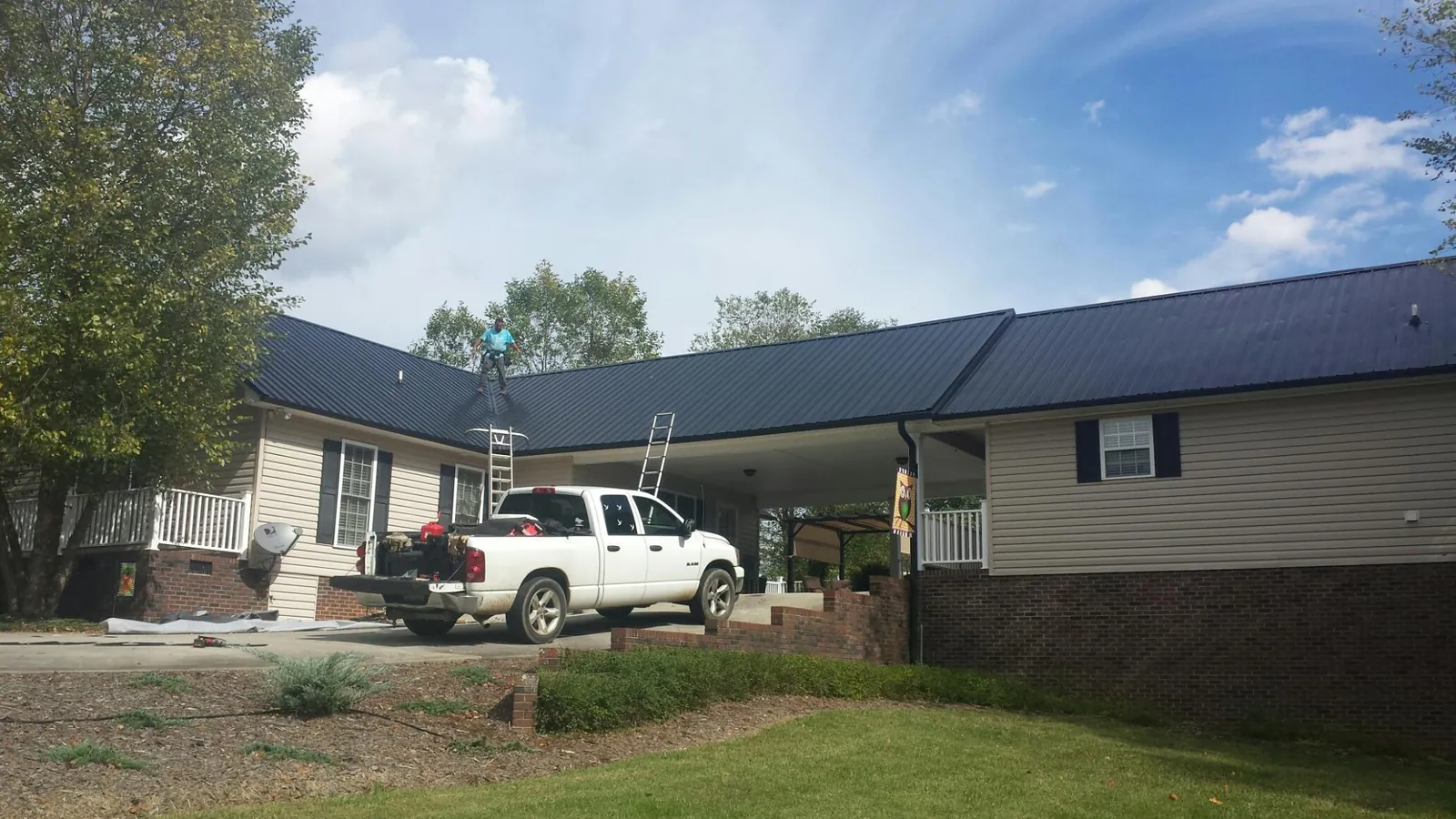 Black metal roof over a home and attached breezeway with ladders set in Flanagan