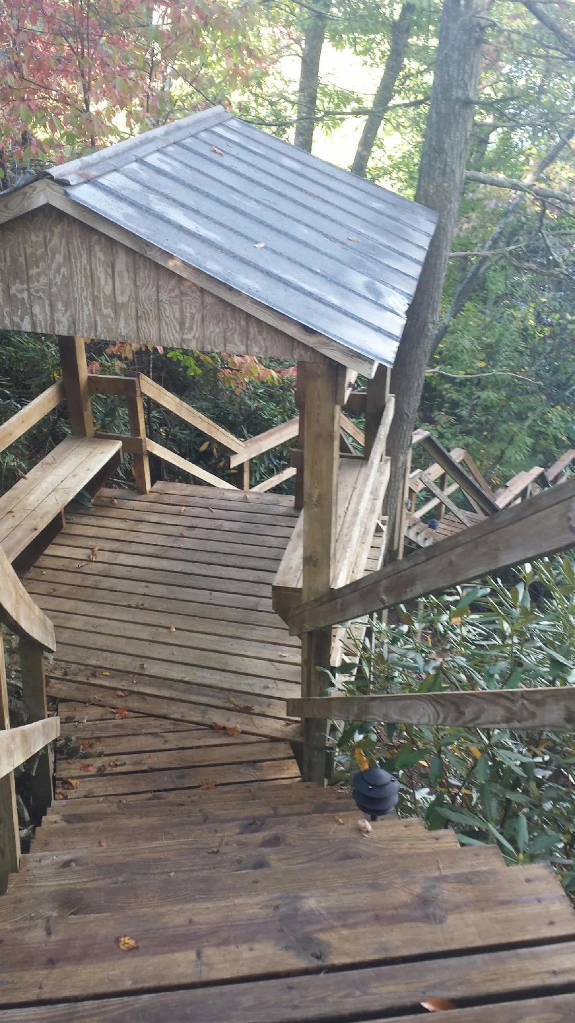 Metal roofed shelter over wooden steps on a wooded walkway — Skylight Repair & Installation work by our crew in Flanagan