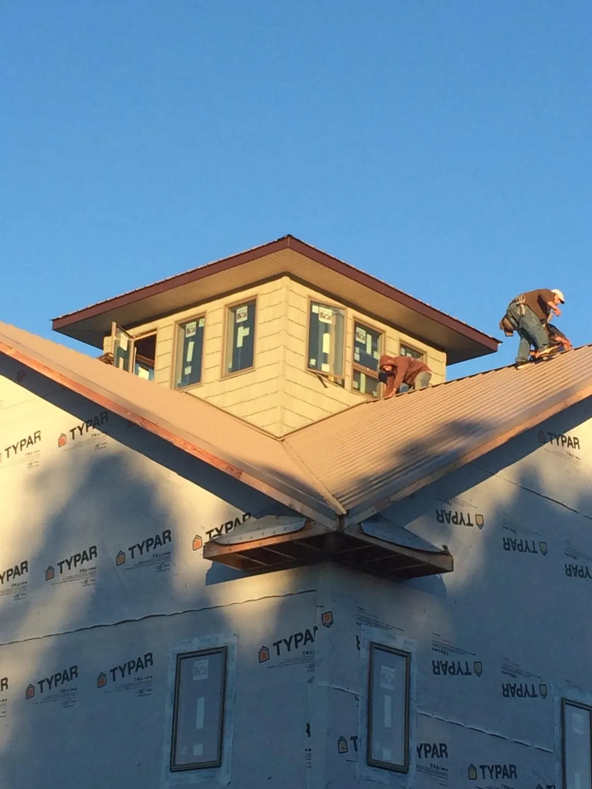 Roofers working around a rooftop cupola on a new metal roof at sunset — Roof Waterproofing in Flanagan by Roofing Brothers